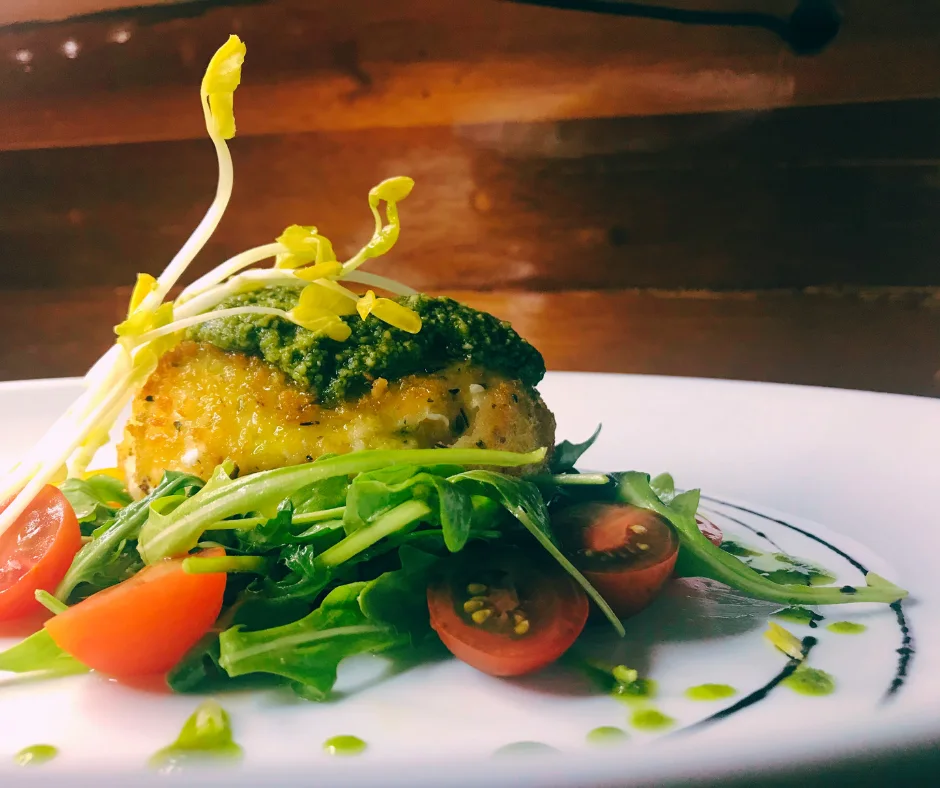 Fried burrata over arugula salad with cherry tomatoes, basil and pesto