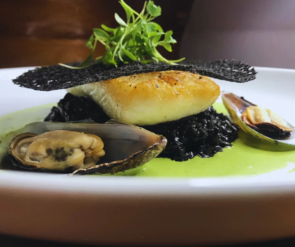 Halibut filet over squid-ink risotto with New Zealand green mussels at Niche Restaurant