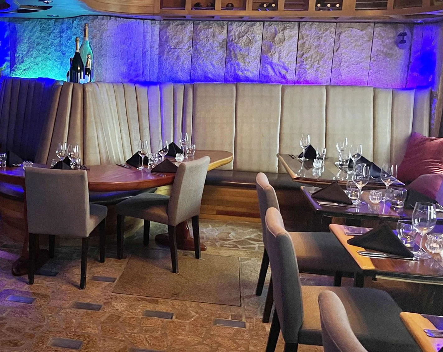Candlelit dining room at Niche Restaurant with banquette seating and violet-lit stone walls